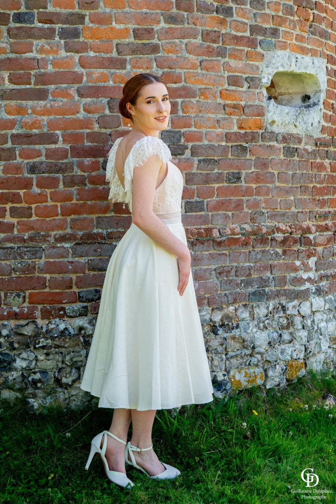Robe de mariée midi en lin écru et son buste en crêpe satiné nude, ornée de sa dentelle façon chantilly.