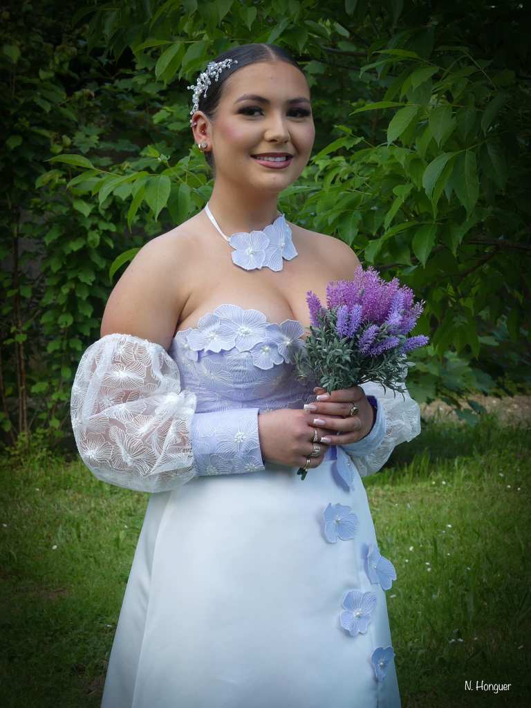 Robe de mariée en satin duchesse blanc cassé et doupion lavande, ornée de fleurs.
