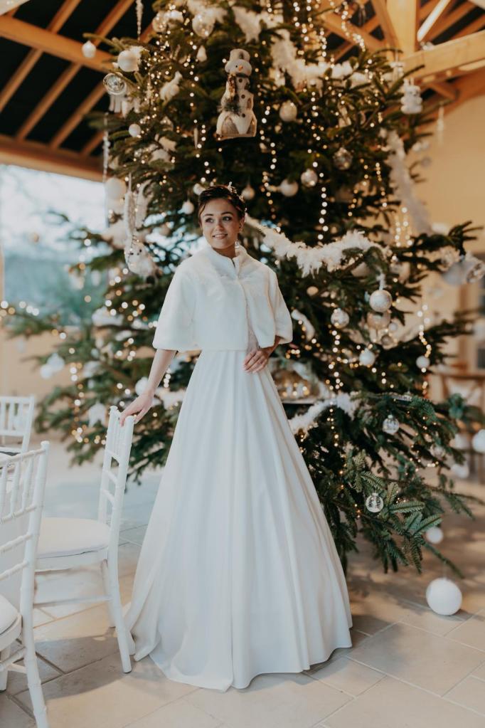 Une robe de mariée intemporelle, ornée de sa cape en fausse fourrure pouvant s'adapter à différentes robes pour se mariée en hiver et plus particulièrement à Noël.