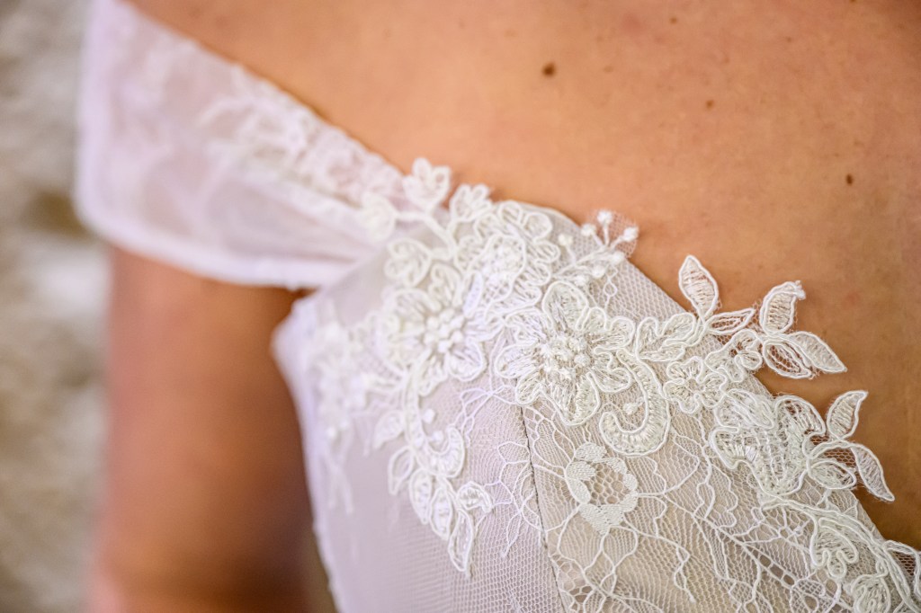 Détail d'une robe beige avec des broderies blanches.